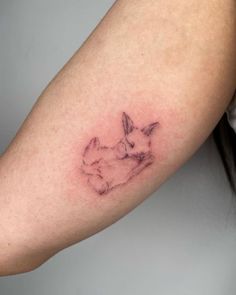 a woman's arm with a small tattoo of two rabbits sitting on top of each other