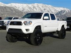 a white truck parked in a parking lot with mountains in the backgrouund