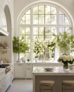 a large kitchen with an arched window and marble counter tops, along with two stools