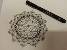 a pen is sitting on top of a paper with a drawing of a flower of life