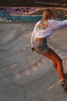 a woman riding a skateboard up the side of a ramp at a skate park