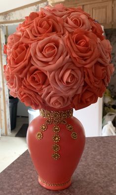 a red vase filled with pink roses on top of a table