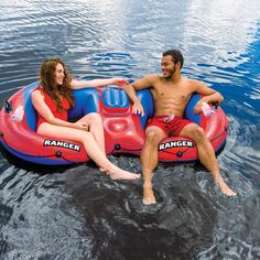 a man and woman sitting on top of an inflatable raft floating on the water