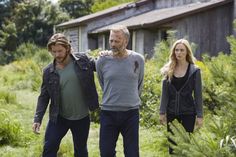 two men and a woman walking through tall grass