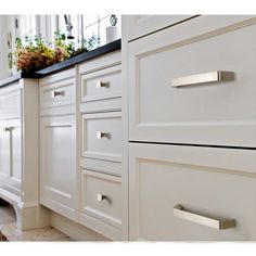 an image of a kitchen setting with white cabinets and stainless steel handles on the drawers