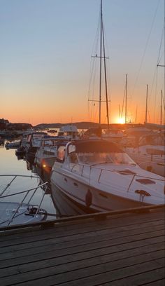 the sun is setting over boats docked in the harbor