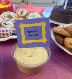 a table topped with lots of cakes and cupcakes next to a sign that says project hummus