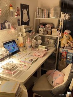 a desk with many items on it and some stuffed animals in the corner next to it