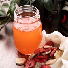 a jar filled with liquid sitting on top of a table next to some fruit and nuts