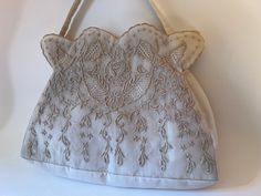 "This lovely handbag is made of a beautiful cream nylon organdy fabric, with a machine-embroidered border design, including fine cutwork and French knots. The top edges are a wide scallop shape. The short single handle is made of the same organdy fabric. Zipper closure and single interior pocket. Excluding the handle, the bag measures 8 1/8\" long x 11\" wide. The base and side gusset are 2\" wide." Vintage Cream Bags With Detachable Handle, Vintage White Embellished Bags, Vintage Embroidered Cream Bag, Vintage Rectangular Bag With Pearl Embroidery, Organdy Fabric, Vintage White Embellished Evening Bag, Embroidered Border, Vintage Bag, French Knots