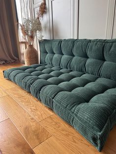 a green couch sitting on top of a hard wood floor