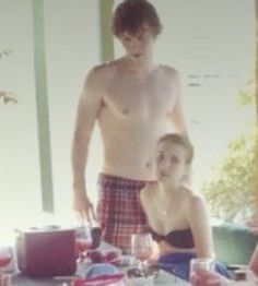 a man and woman standing in front of a table with food on top of it