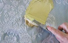 a person using a knife to paint a piece of fabric with yellow paint on it