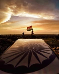 two people holding a flag on top of a car