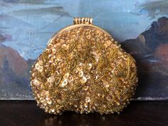 This beautiful gold sequin beaded clutch or purse is in good vintage condition with a fully functional kiss clasp. The clutch has imperfections (shown), but they only add to its overall charm. So pretty! The purse measures roughly 4-5/8" long by 1" deep by 4-3/8" tall and is ready for your next party! See additional vintage accessories, art, pottery, and decor here - https://www.etsy.com/shop/7Arrow?ref=dashboard-header. Please note that the photos are a significant part of the description, so review each closely. These are vintage/antique pieces and not perfect. The paintings pictured in the background are not included in the purchase or for sale. All items are sold as-is with no returns, exchanges, or refunds. I strongly believe in reuse/recycling, so your purchase will arrive as quickly Gold Embellished Evening Bag As Gift, Gold Sequined Evening Bag For Events, Gold Sequined Evening Bag For Formal Occasions, Gold Evening Bag With Sequins For Wedding, Gold Sequined Evening Bag For Wedding, Vintage Gold Evening Bag For Festive Occasions, Festive Beaded Gold Evening Bag, Handmade Gold Coin Purse For Parties, Gold Beaded Evening Bag For Events