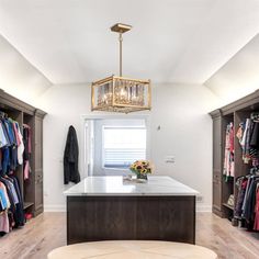 an open closet with clothes on hangers and a chandelier hanging from the ceiling