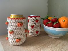 crocheted strawberries and oranges are sitting next to two cups on a table