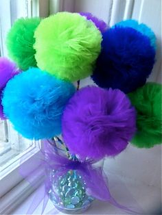 a vase filled with colorful pom poms on top of a window sill