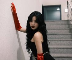 a woman with long black hair wearing red gloves