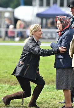 a woman kneeling down next to a man on top of a field