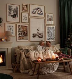 two people sitting on a couch in front of a christmas tree with lit candles next to them