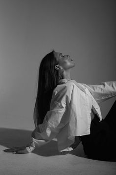 a woman is sitting on the floor with her legs crossed and looking up to the sky