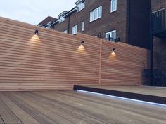 a wooden deck with three lights on it and some brick buildings in the back ground