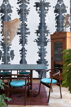 a dining room table with blue chairs in front of a black and white wallpaper