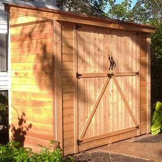 a large wooden shed sitting next to a white house with a tree in the background