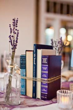 a table with books and vases on top of it next to candles, candle holders and flowers