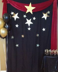 a black and gold themed party with balloons, cake table and curtain in the background