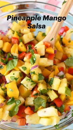 pineapple mango salsa in a glass bowl with a wooden spoon and title above it