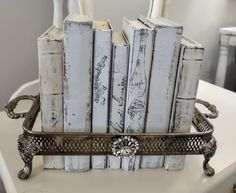 several white books are stacked on top of each other in a silver tray with ornate handles