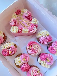 cupcakes with pink and white frosting are in a box on the table