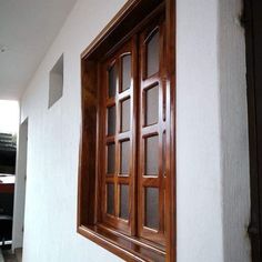 an open window on the side of a white wall next to a black and brown door