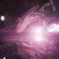 a person holding something in their hand with pink light coming out of the palm and fingers