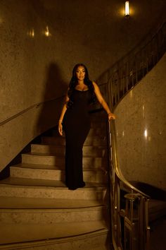 a woman in a black dress standing on some stairs