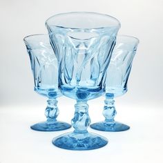 three blue glass goblets sitting next to each other