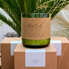 a green candle sitting on top of a cardboard box next to a potted plant