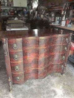 an old dresser has been painted red and gold with intricate designs on the top, along with other antique furniture