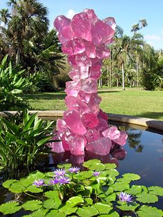 a pink sculpture sitting on top of a pond filled with water lilies