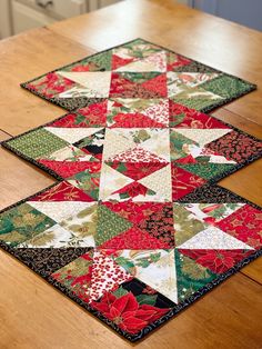 two quilted placemats sitting on top of a wooden table