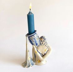 a blue candle is sitting on top of a ceramic elephant figurine with a pillar in the shape of an elephant