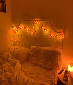 a bed with lights on the headboard and night stands in front of it,