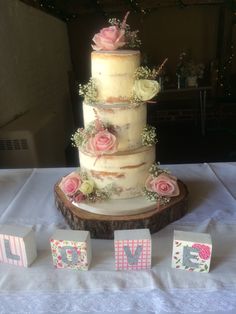 a three tiered cake sitting on top of a table next to blocks with flowers