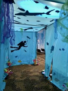 an underwater themed room with blue drapes and fish on the ceiling, under water