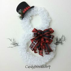 a snowman wreath with a black top hat and red plaid ribbon on the front