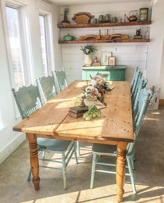 a wooden table surrounded by blue chairs in a room with open shelves on the wall