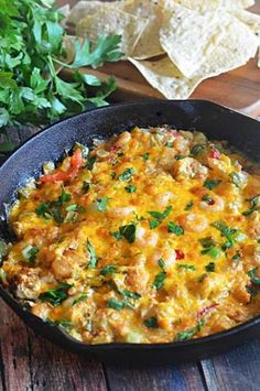 a skillet filled with mexican food and tortilla chips on a wooden table