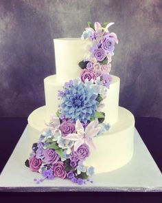 a three tiered white cake with purple flowers on top